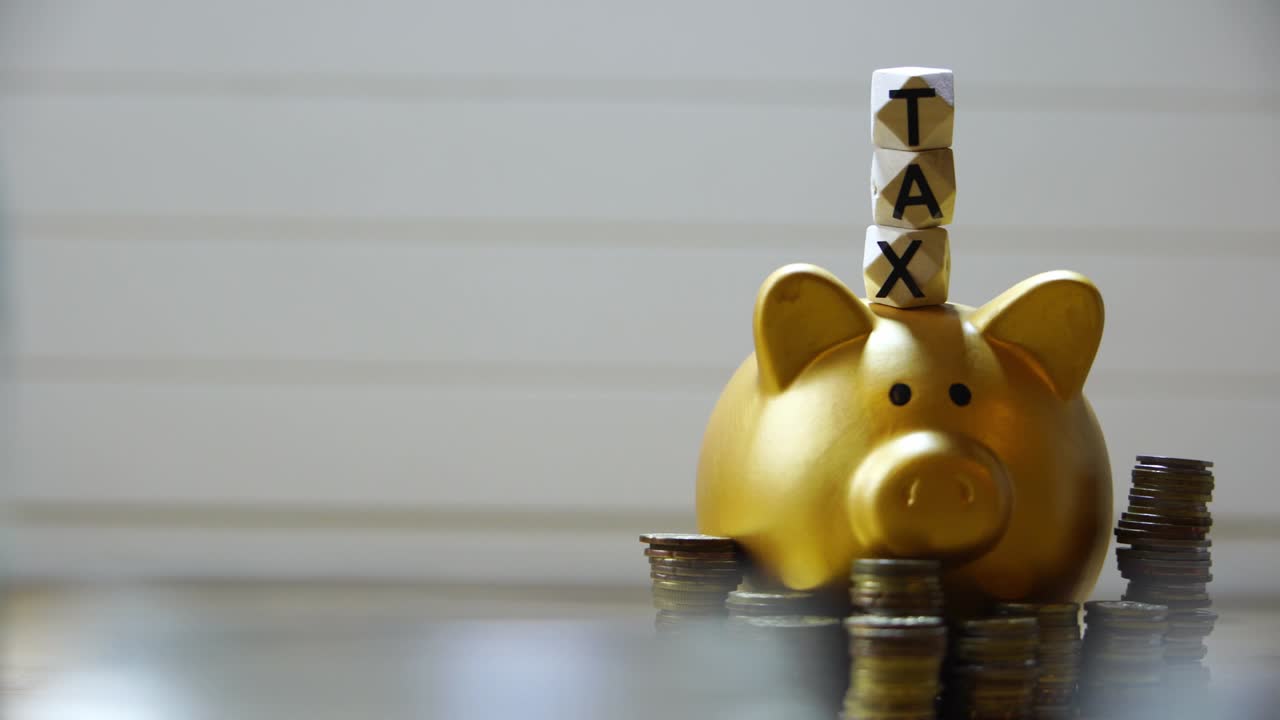 「TAX」と書かれたビーズが付いた金色の貯金箱