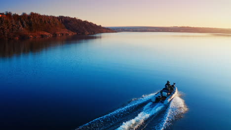 two fishermen in motor boat in the evening. speedboat moving on the water surface at sunset. aerial view.