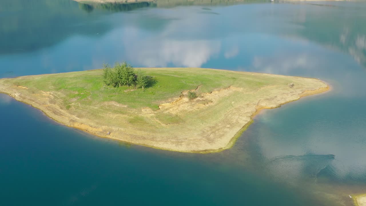 lago rama en bosnia y herzegovina con pájaro garza aterrizando en la isla de luke en un día tranquilo, tiro aéreo a la izquierda