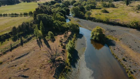 Toma-Aérea-Inclinada-Hacia-Arriba-De-Un-Pequeño-Río-En-El-Campo-De-Nueva-Zelanda