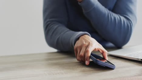 Vídeo-De-Un-Hombre-De-Negocios-Birracial-Usando-Una-Computadora-Portátil-Y-Un-Teléfono-Inteligente-Con-Fondo-Blanco