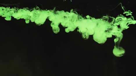 slow motion video of green watercolor ink mixing in water against black background