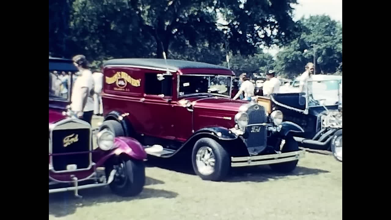 Group of People at 1970s US Old Car Show, Gathered Around Vintage Automobiles. CIRCA USA - 1970s: Attendees of a 1970s US old car show stand together, admiring and discussing a collection of vintage automobiles.