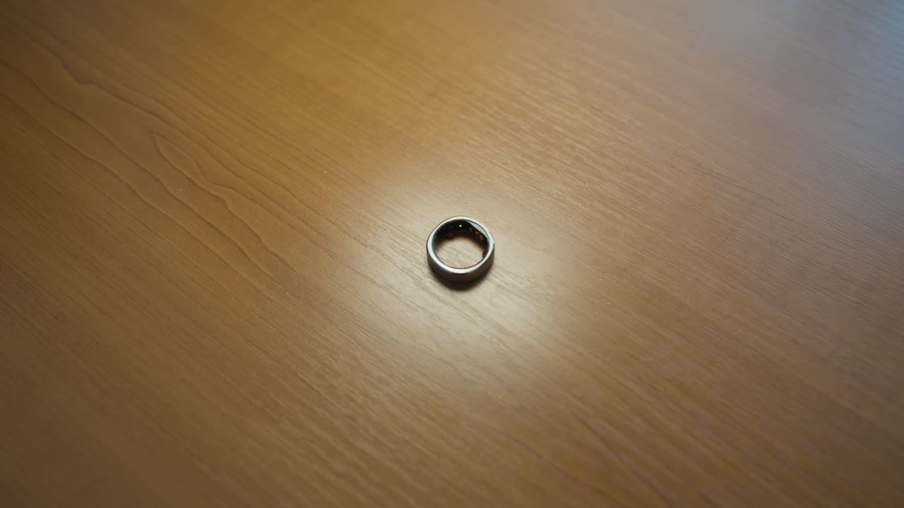 A smart silver ring lies on the table, flashing different colors. Modern technology that supports health and monitoring