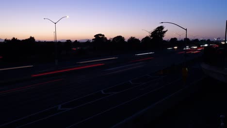 vehicles stream steadily along i-80 in berkeley, their lights forming continuous ribbons of motion under fading daylight.