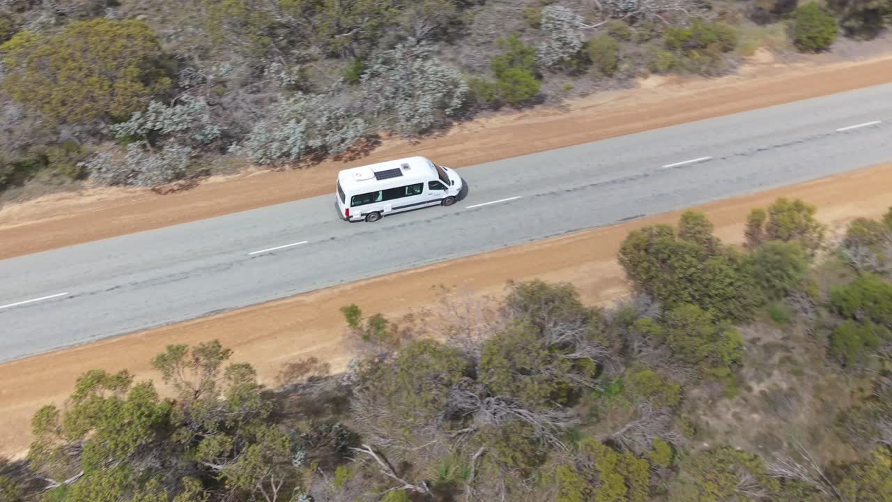 Cinematic drone spotlight shot of an RV driving along a desolate straight road in the Western Australia outback