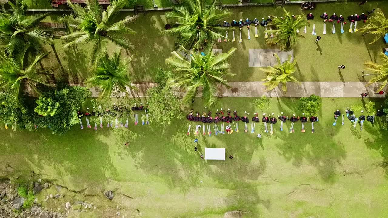 Ripresa aerea con drone di file di attrezzature da rafting e barche sulla riva del fiume, sul prato