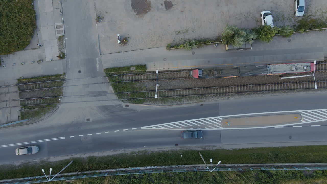 Train departing train station beside driving cars on the road,top down aerial