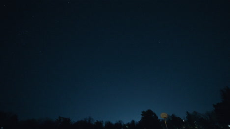shooting star passes through the sky over an empty basketball court at night