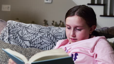 Young-girl-reading-book-in-living-room