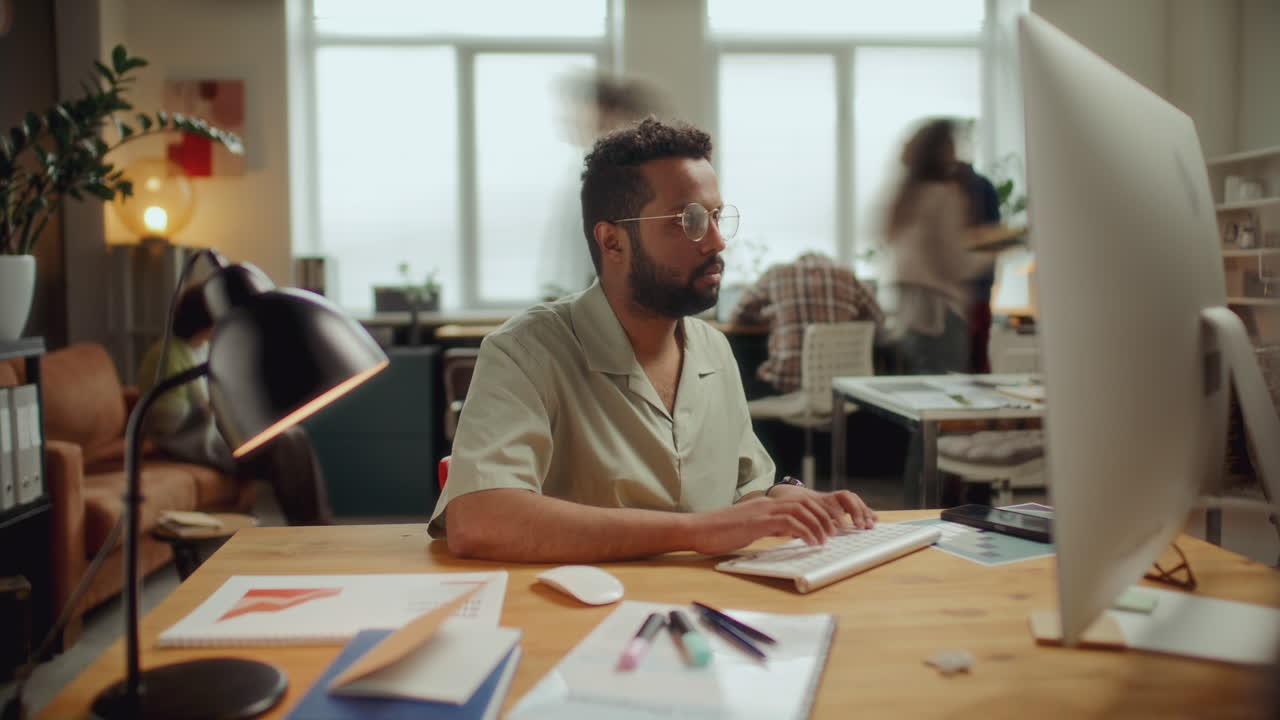 Timelapse af fokuseret mand, der arbejder på stationær computer på åbent kontorlandskab