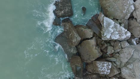 Aerial-birdseye-view-of-abandoned-seaside-fortification-buildings-at-Karosta-Northern-Forts-on-the-beach-of-Baltic-sea-,-overcast-winter-day,-wide-ascending-drone-shot-moving-forward