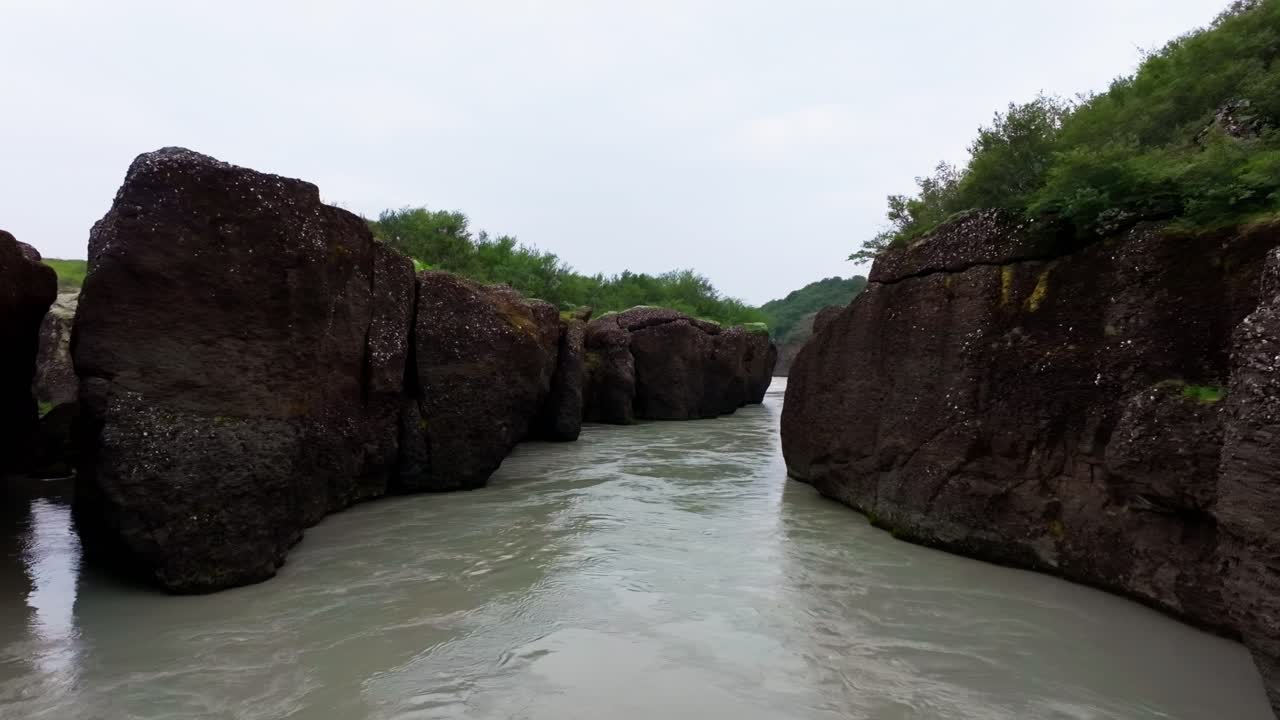 Filmato aereo 4K realizzato con drone di un ampio fiume che scorre tra le alte pareti del canyon in Islanda, che rivela la scala spettacolare, le scogliere frastagliate e la potente geologia naturale
