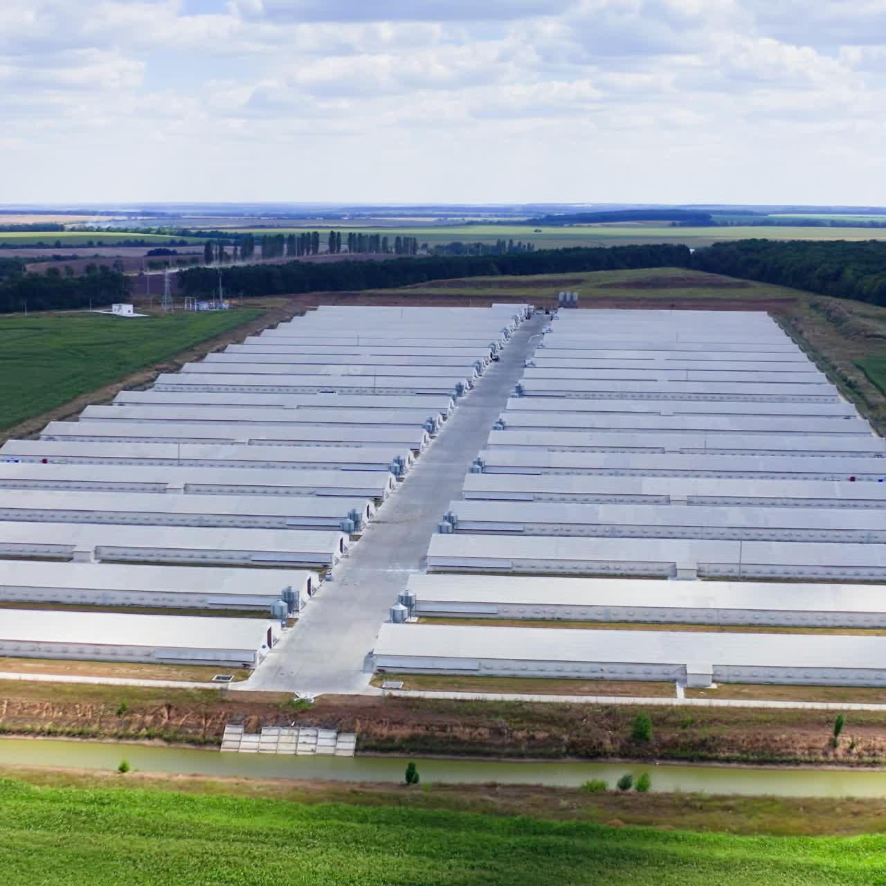 Large modern farm in the countryside. Rows of white farmhouses on field. Agricultural complex on green landscape. Aerial view