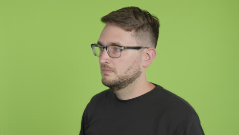 man in glasses removes protective kn95 face mask while looking left of camera on green screen chroma key