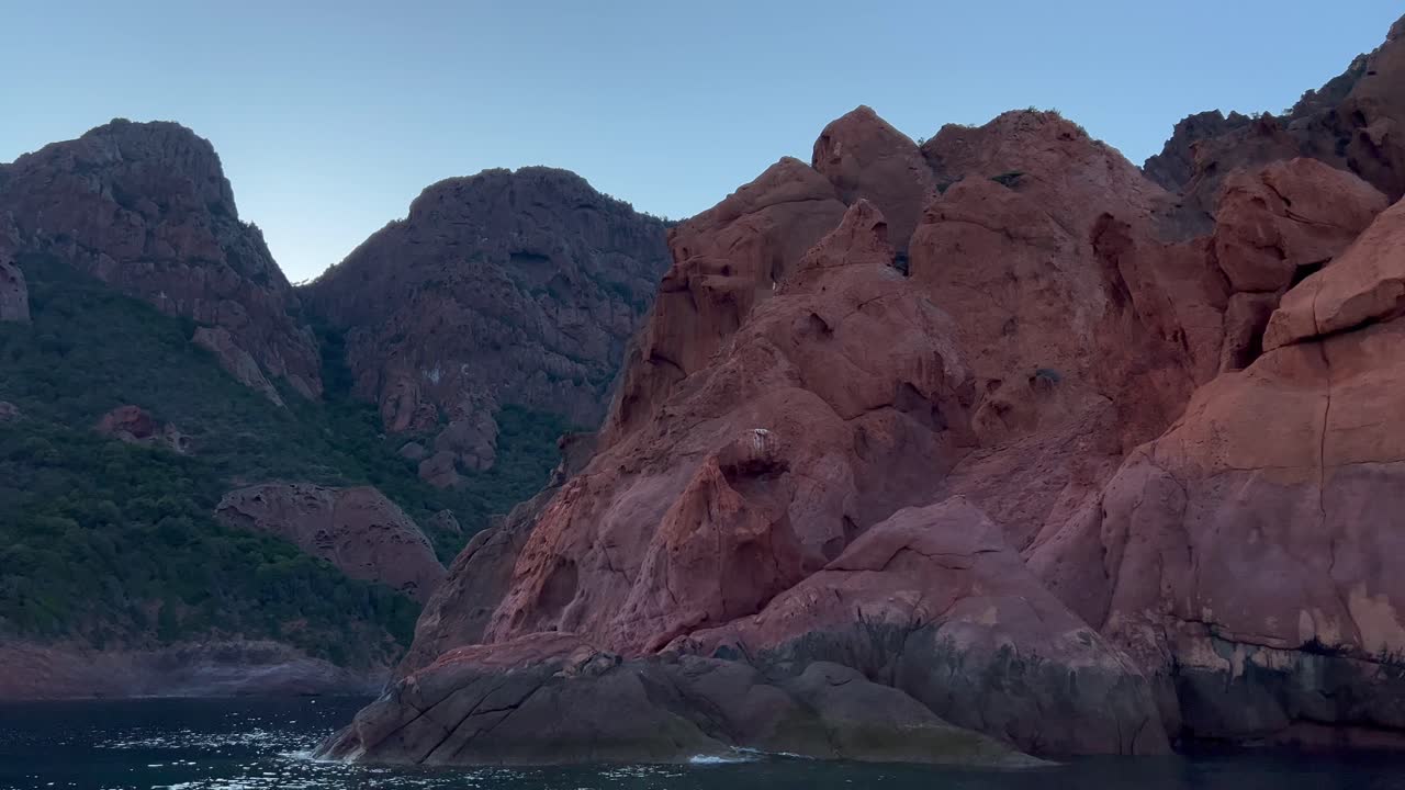 Eroded red rocks of Scandola UNESCO nature reserve seen from sailing boat in summer season, Corsica island in France