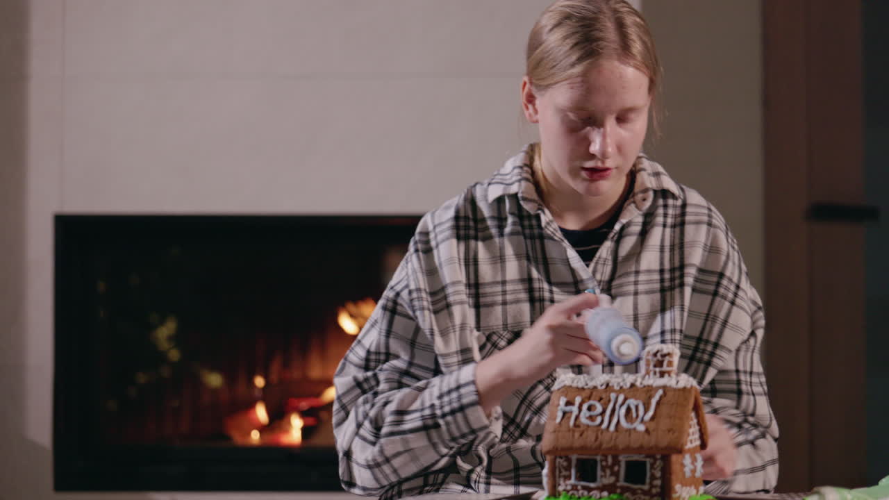 십대 소녀 가 벽난로  에 있는 생강  집 을 장식 하고 있다