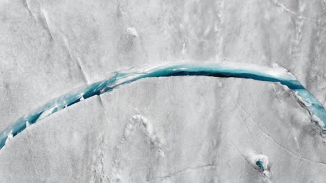 aerial: large glacier crevasse in ice sheet iceberg, 4k top down shot