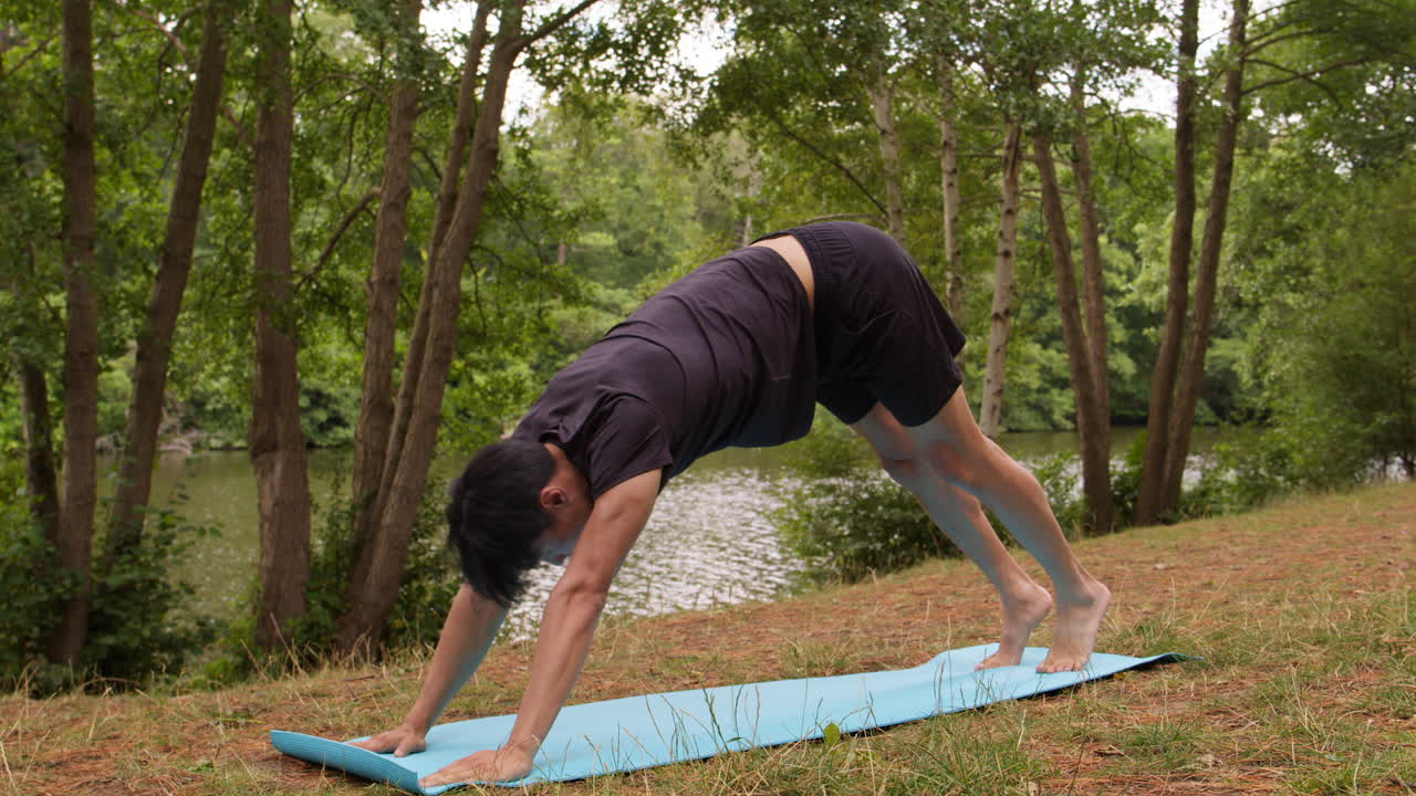 hombre con ropa deportiva haciendo yoga en una alfombra en el bosque junto a un lago o río disfrutando de la paz y la belleza de la naturaleza 2