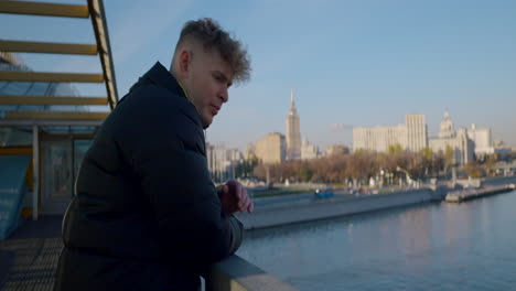 man contemplating cityscape from bridge