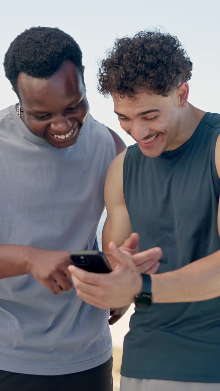 Two Young Men Laughing While Looking at a Smartphone