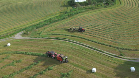 tractors on farmland collecting fodder and making bales, wraps them in plastic, aerial