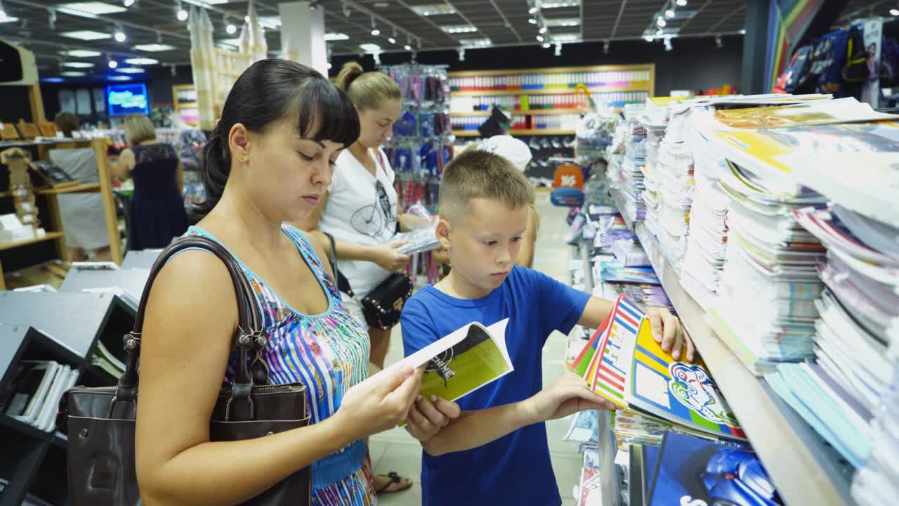 VINNITSA, UKRAINE - AUGUST 20, 2018: Back to school concept. Young mother and little boy buying school supplies in store.