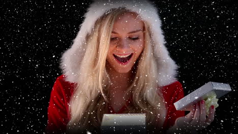 video composition with falling snow over girl in santas suit holding gift