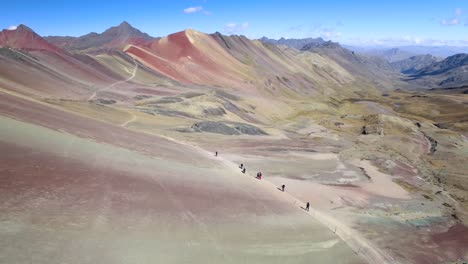 aerial view of hikers trekking alongside rainbow mountain in the andes of peru