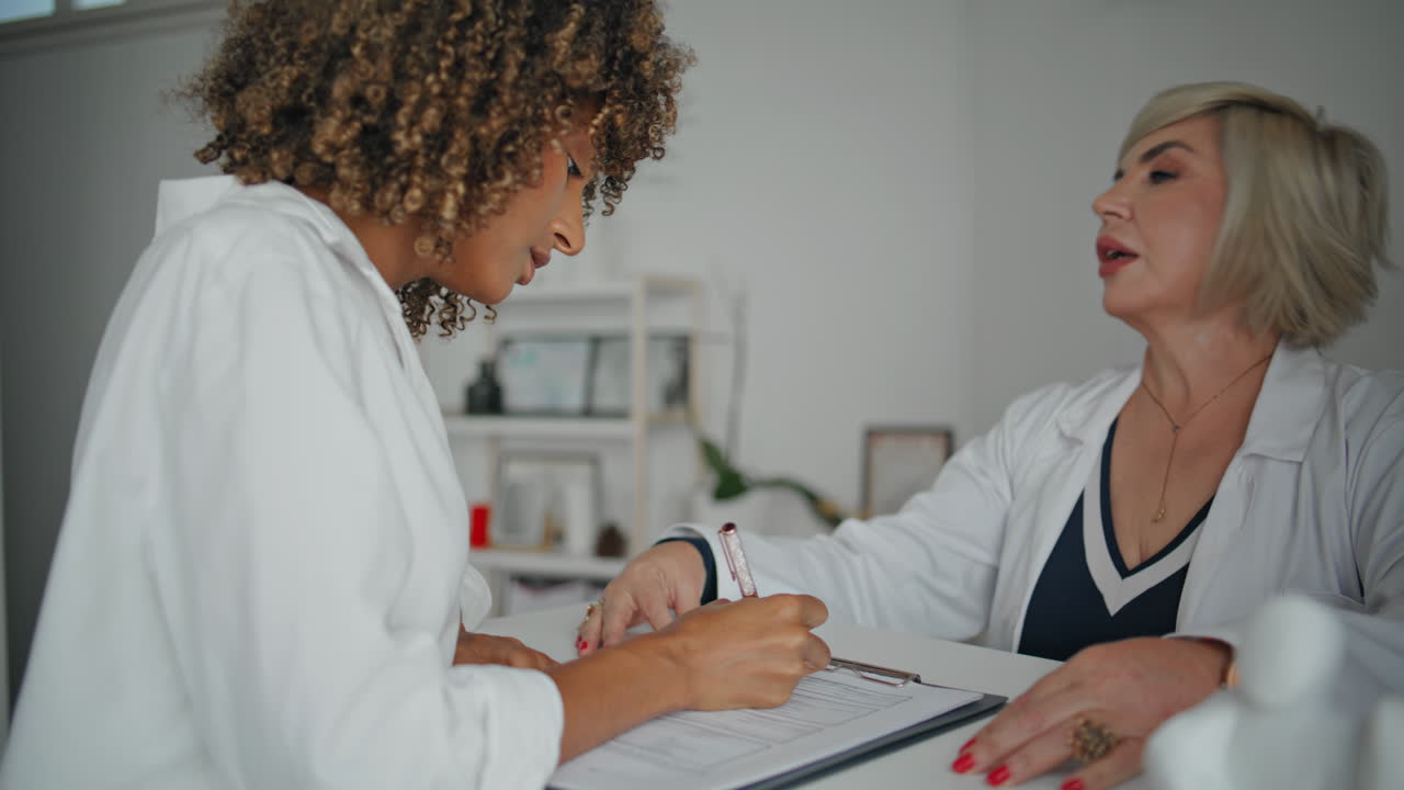 una mujer firmando un formulario médico en una clínica moderna. una enfermera amigable hablando.