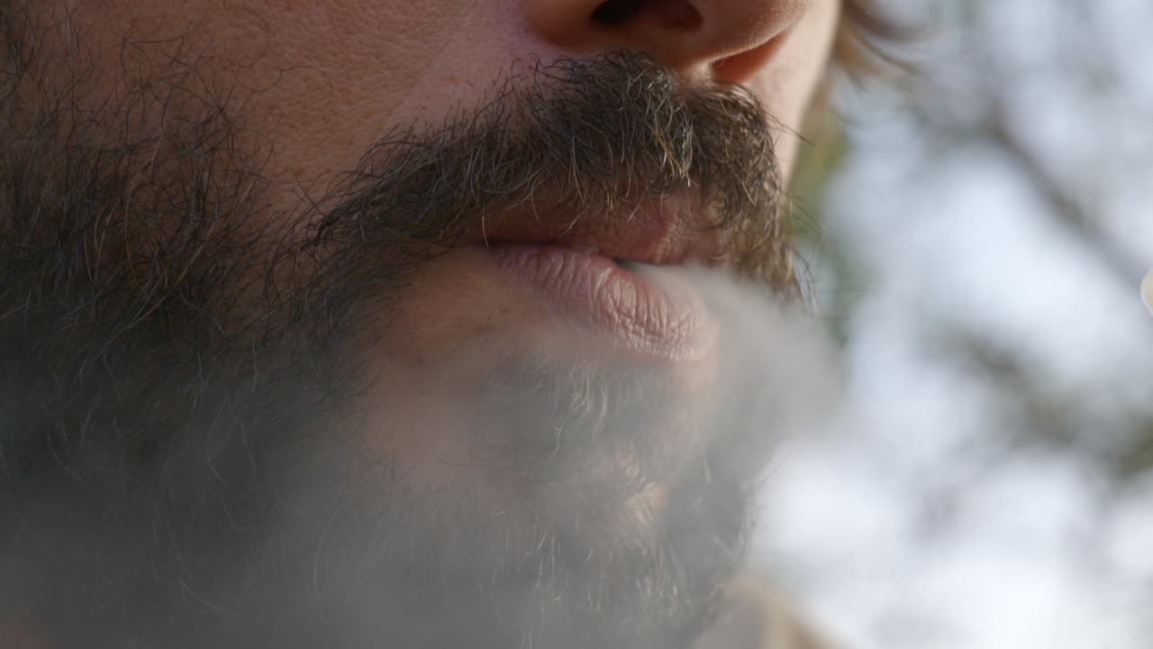 primer plano de la boca del hombre barbudo expulsando humo después del golpe de shisha