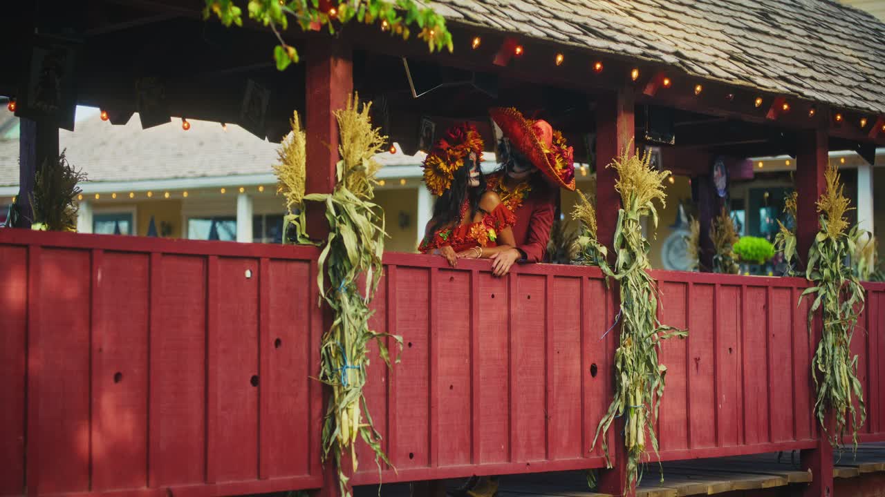 Couple in Day of the Dead Costumes on a Red Wooden Bridge