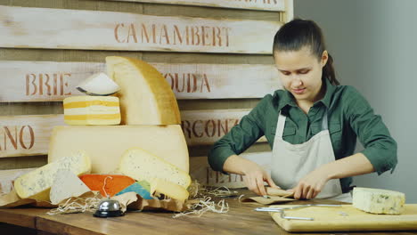 el vendedor empaca un trozo de queso cerca hay una gran cabeza de queso detrás del fondo de madera con th