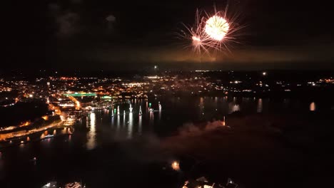 beautiful fireworks with drone and city lights reflected in water