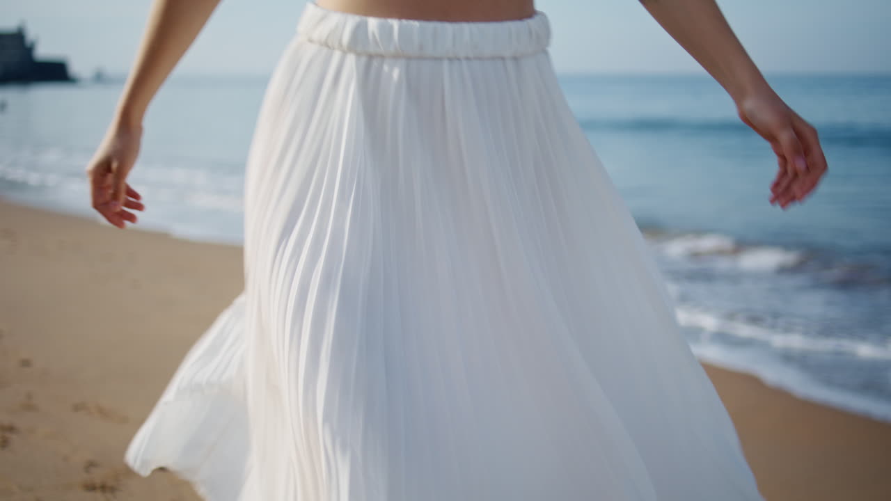 неузнаваемая девушка, гуляющая по берегу океана в летние выходные. женщина танцует.