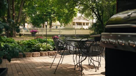 Panning-shot-of-black-patio-chairs,-a-table,-and-a-grill-in-the-foreground