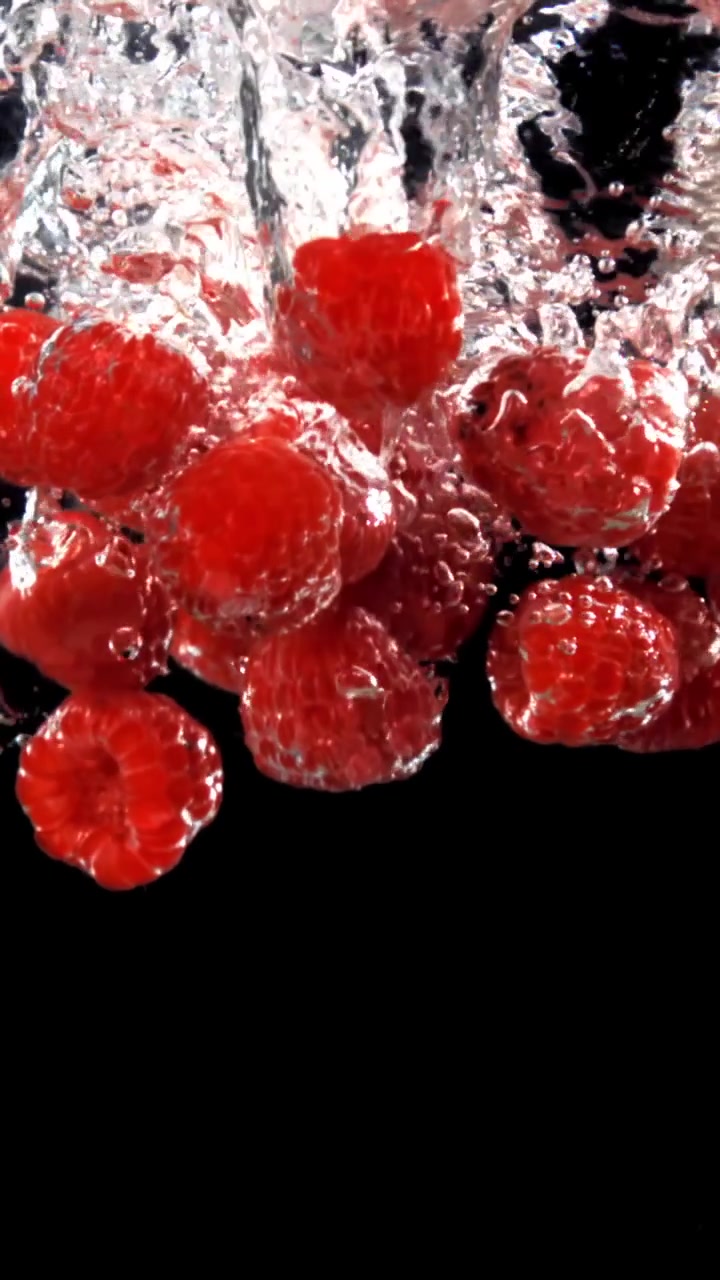 Slow Motion of Red Raspberries Dropping into Clear Water