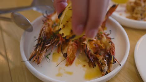 lemon squeezed over grilled prawns on plate