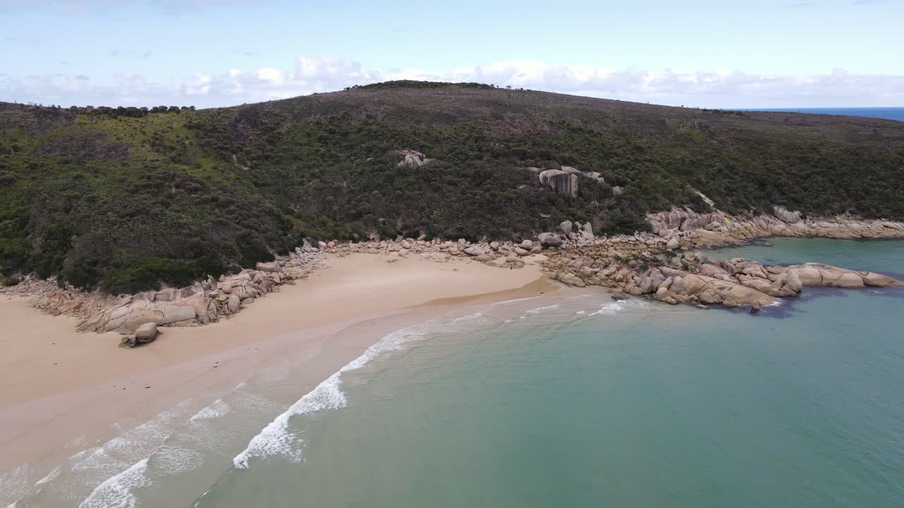antena de drones avanzando y panorámica sobre el hermoso agua azul claro y la montaña verde en un día soleado en el promontorio de wilsons
