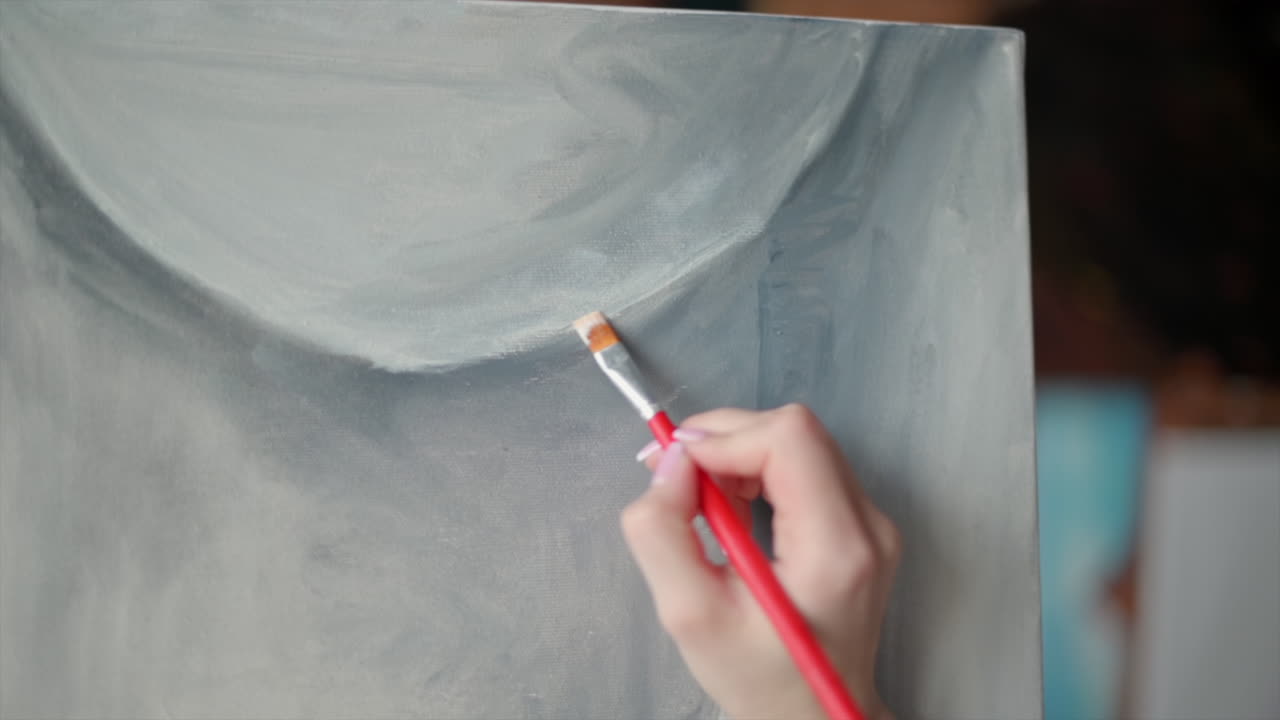 Close up of a woman painting a female body on a canvas at an art gallery workshop