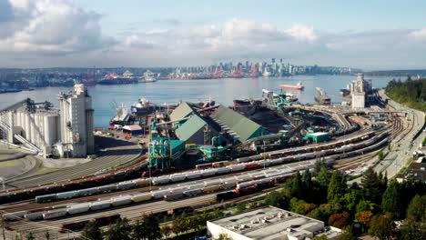 aerial view of oil and natural gas company tank wagons parked on railroad overlooking burrard inlet and downtown vancouver skyline in canada