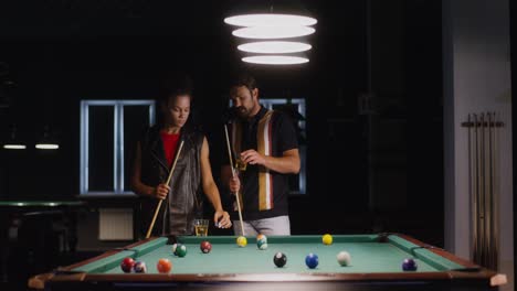 couple playing billiards at night