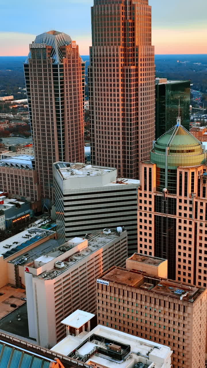 Soft orange light covering the skyscrapers in the uptown of Charlotte, North Carolina, the USA. View on the American city at sunset from top. Vertical video