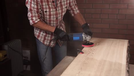 el hombre lijando una tabla de madera con una lijadora eléctrica