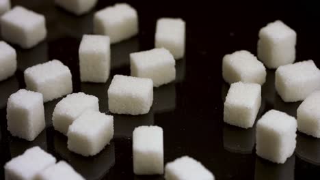 hand arranging sugar cubes on a black surface