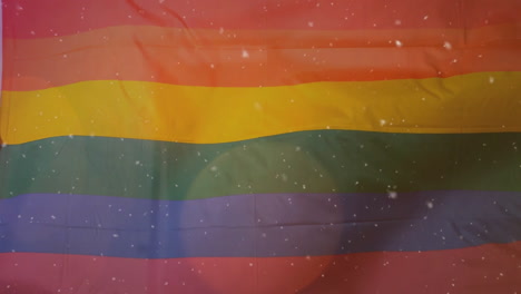 rainbow pride flag fabric unfolding in close-up view, showing confetti flecks and lens-flare glow