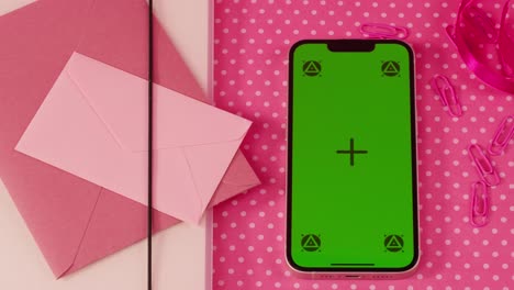 pink smartphone with green screen and envelopes