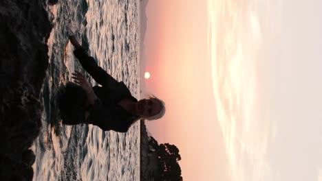 Attractive-blonde-girl-in-the-Adriatic-Sea,-wearing-a-black-shirt-with-glasses,-splashes-and-poses-in-the-water-during-the-sunset-in-Dubrovnik,-Croatia