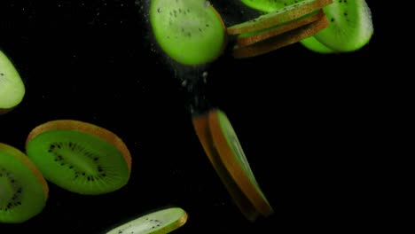 rebanadas redondas de kiwi maduro caen bajo el agua con burbujas de aire.