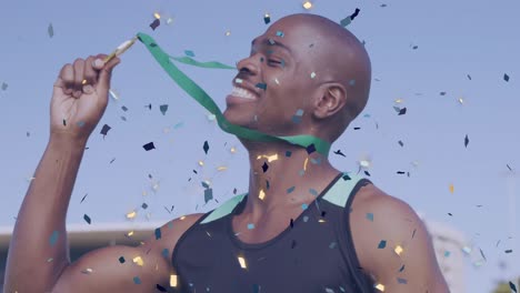 animation of confetti over happy african american sportsman kissing medal and enjoying victory